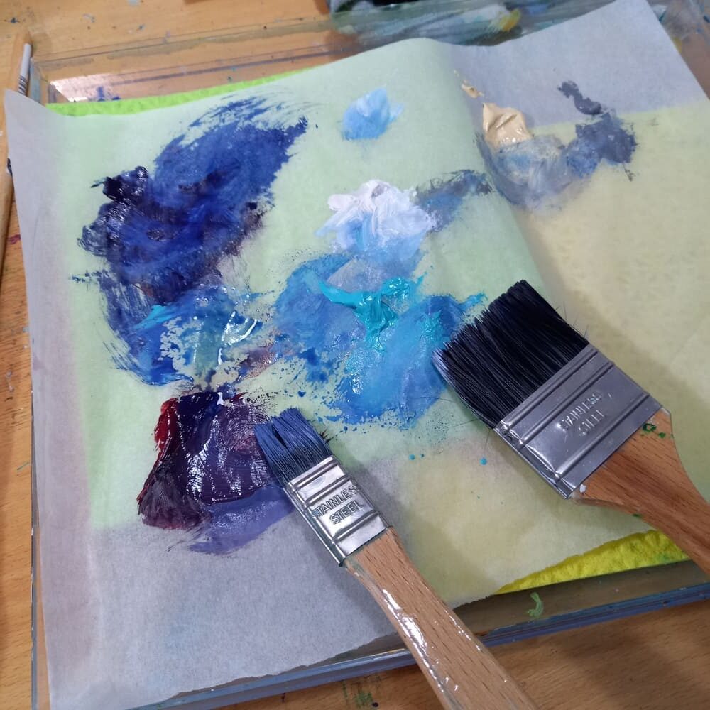 Palette de couleurs bleues et pinceaux dans l'atelier d'Aurélie Rocheta, illustrant sa démarche artistique.